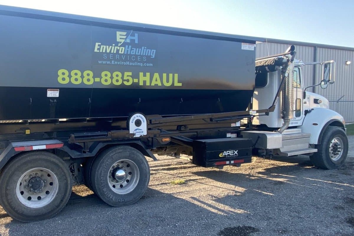 EnviroHauling roll-off container marked 888-885-HAUL loaded on a truck