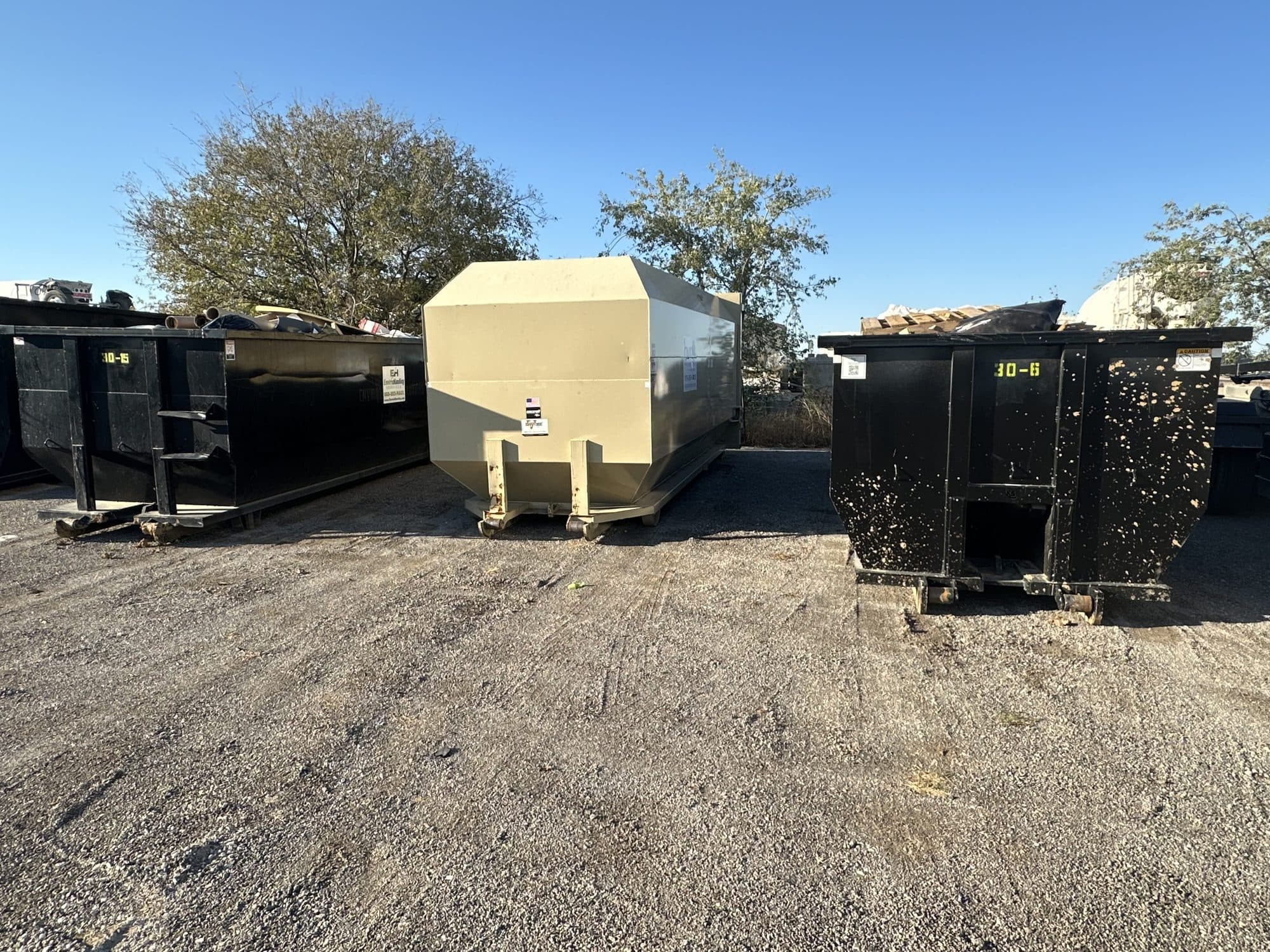 EnviroHauling roll-off containers and a trash compactor in the yard