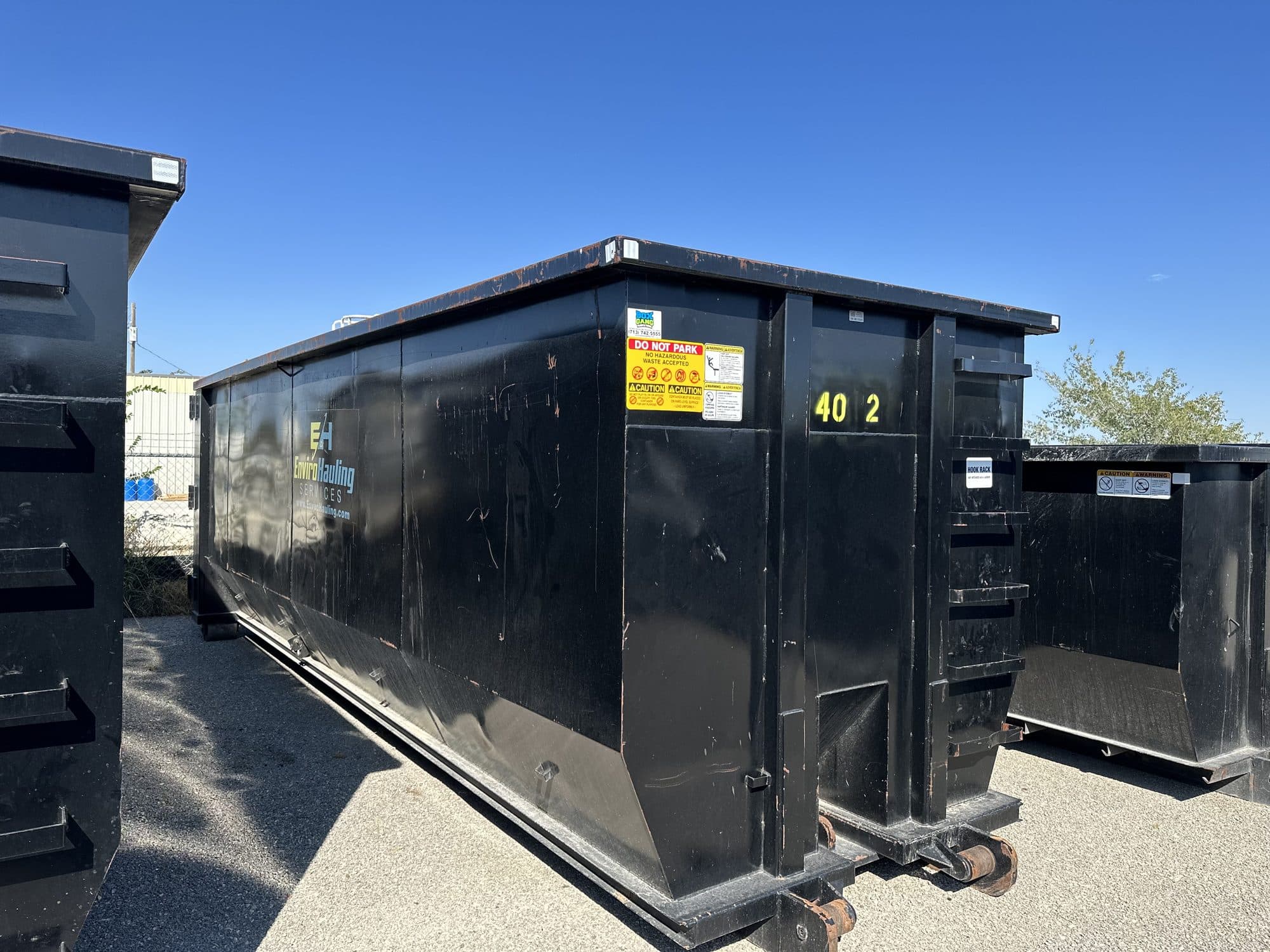 Black EnviroHauling roll-off containers lined up in the yard