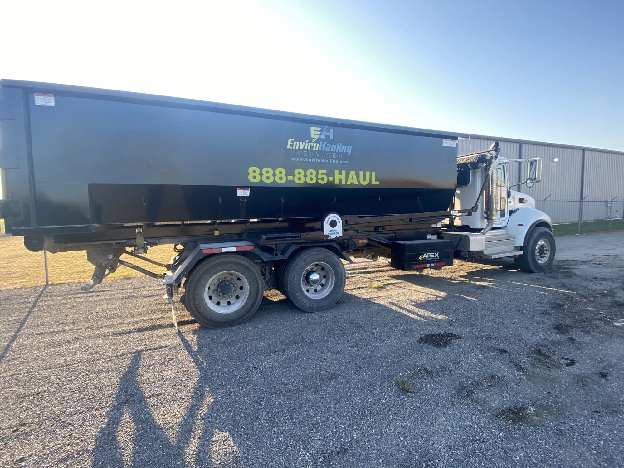 EnviroHauling truck hauling a roll-off container marked 888-885-HAUL