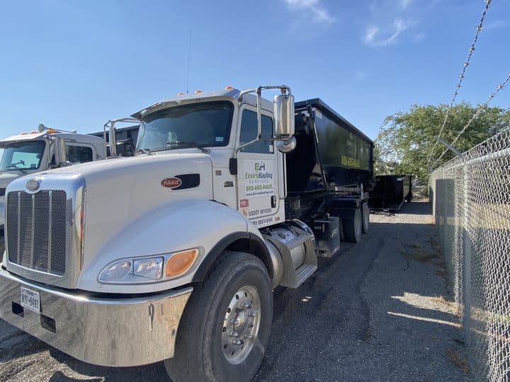 EnviroHauling roll-off trucks parked along the yard fence
