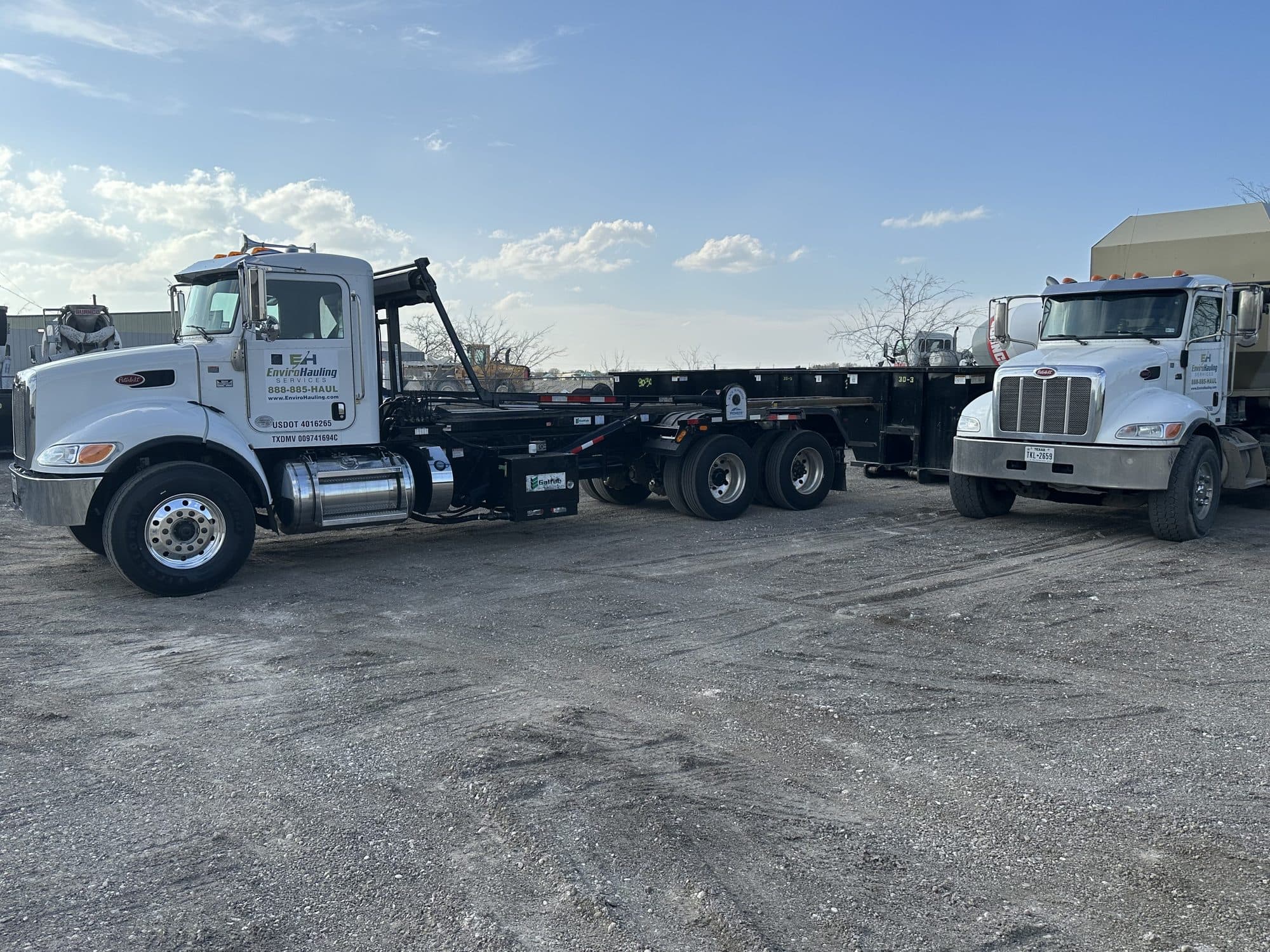 Two EnviroHauling roll-off trucks in the yard