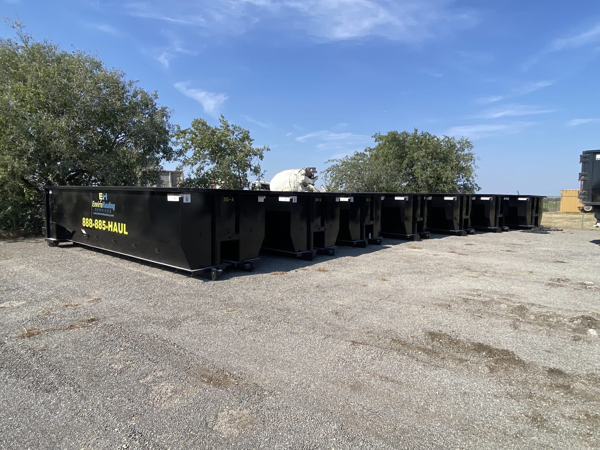 A long row of EnviroHauling roll-off containers marked 888-885-HAUL