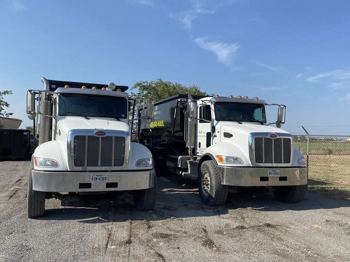 Two EnviroHauling roll-off trucks side by side